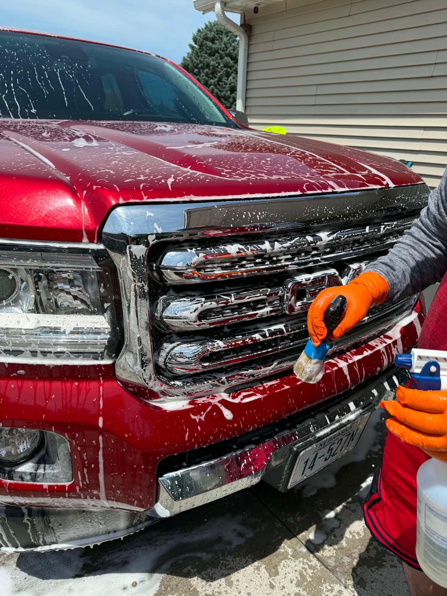 Hand cleaning the grille of a red truck